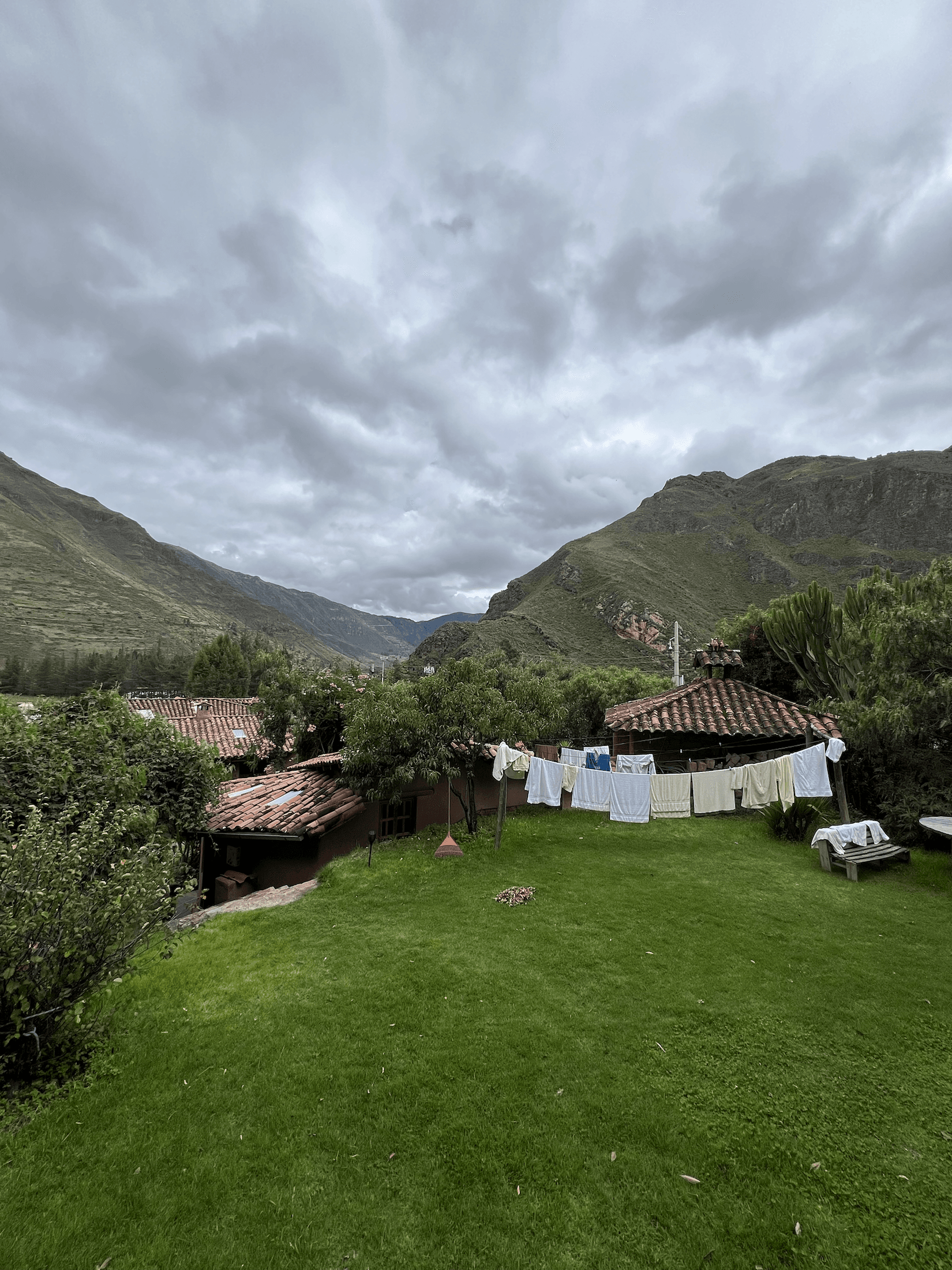 Main lawn of El Molle beside a dramatic rock wall and adobe buildings