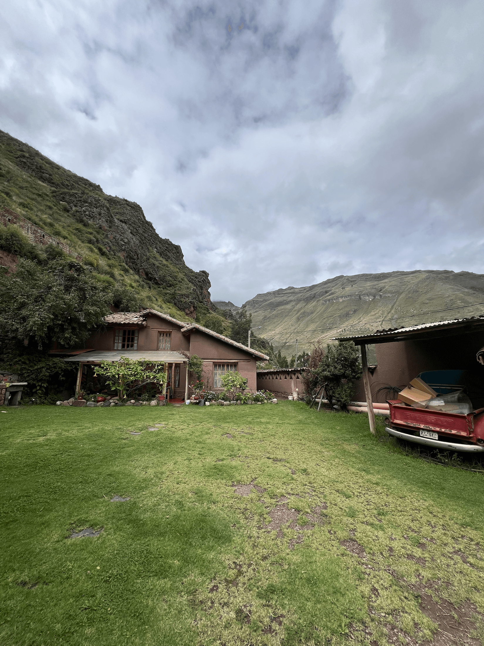 Wide landscape view of El Molle with valley mountains, open lawn, and adobe house buildings