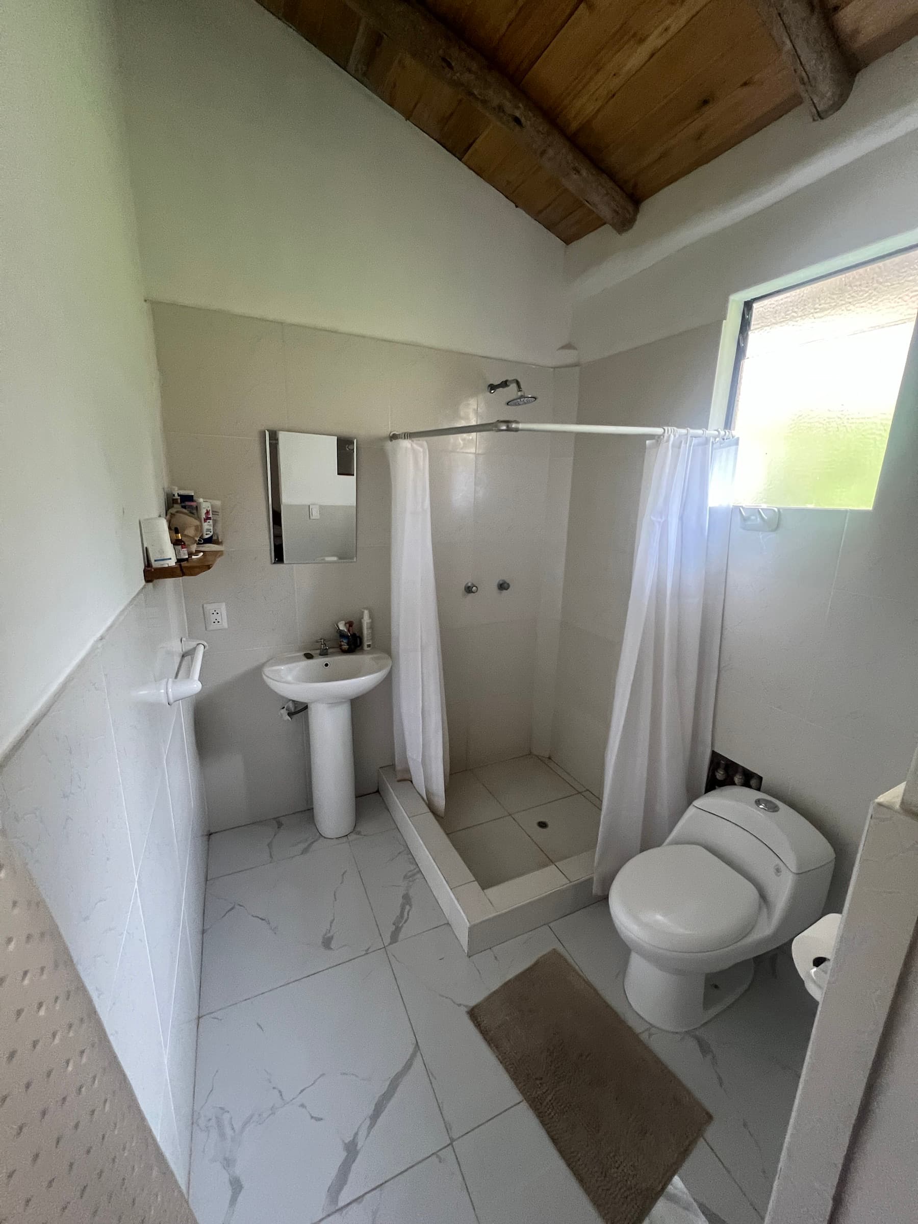 Bathroom with a shower, sink, and natural light prepared for guests