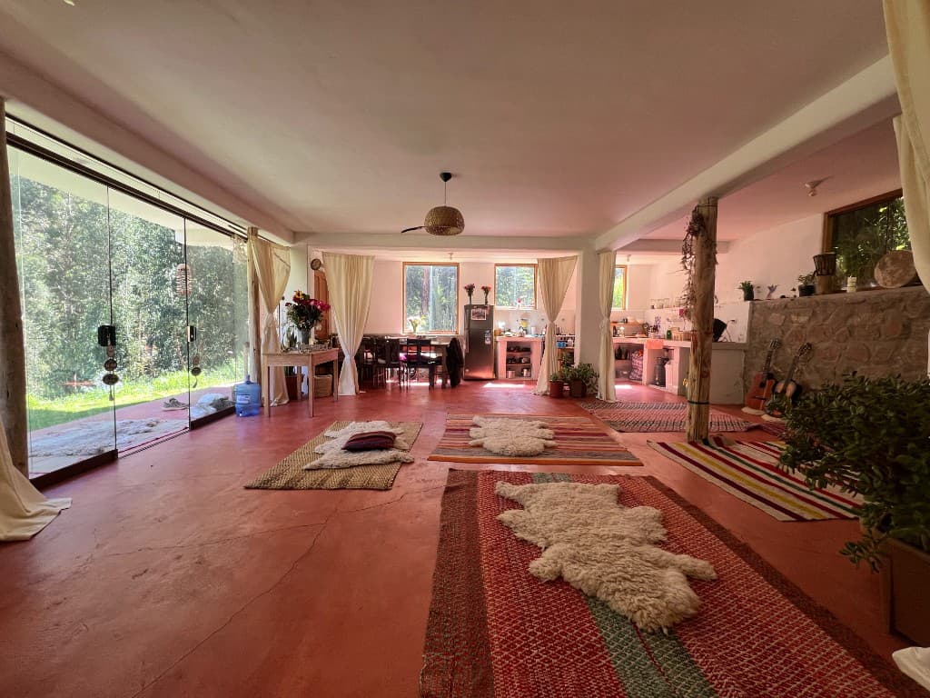 Spacious gathering room with forest views, woven rugs, sheepskins, and acoustic guitars by a stone wall